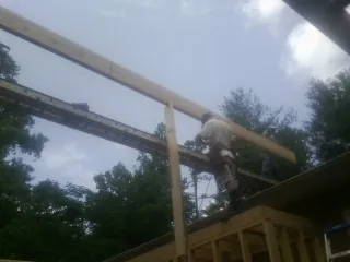 Carpenter setting a ridge beam over a new addition frame — Ice Dam Removal by Roofing Brothers in Center Moriches