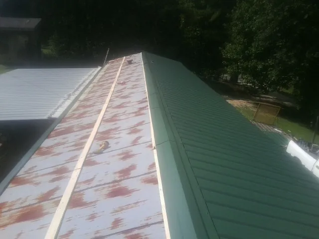 Old rusted panels beside newly installed green metal roofing — Wind Damage Roof Repair by Roofing Brothers in Center Moriches