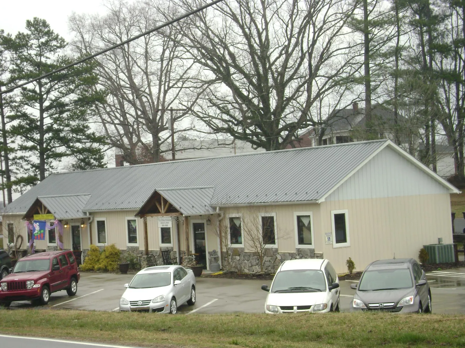 Gray metal roof with timber entry brackets on a small commercial building in Center Moriches