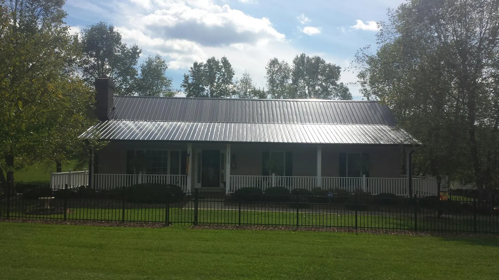 Gray metal roof on a brick ranch with a full width front porch — Gutter Guard Installation work by our crew in Center Moriches