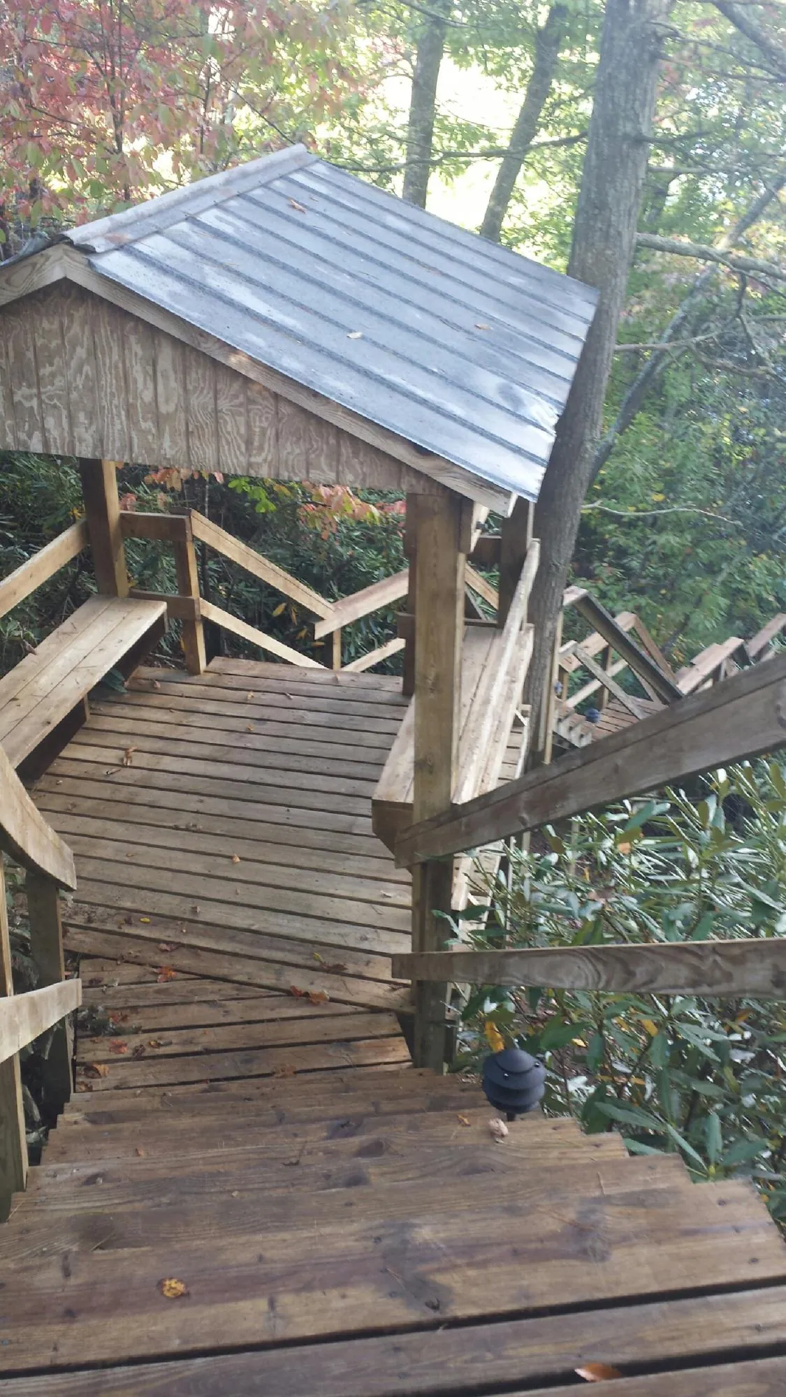 Metal roofed shelter over wooden steps on a wooded walkway — Skylight Repair & Installation work by our crew in Center Moriches