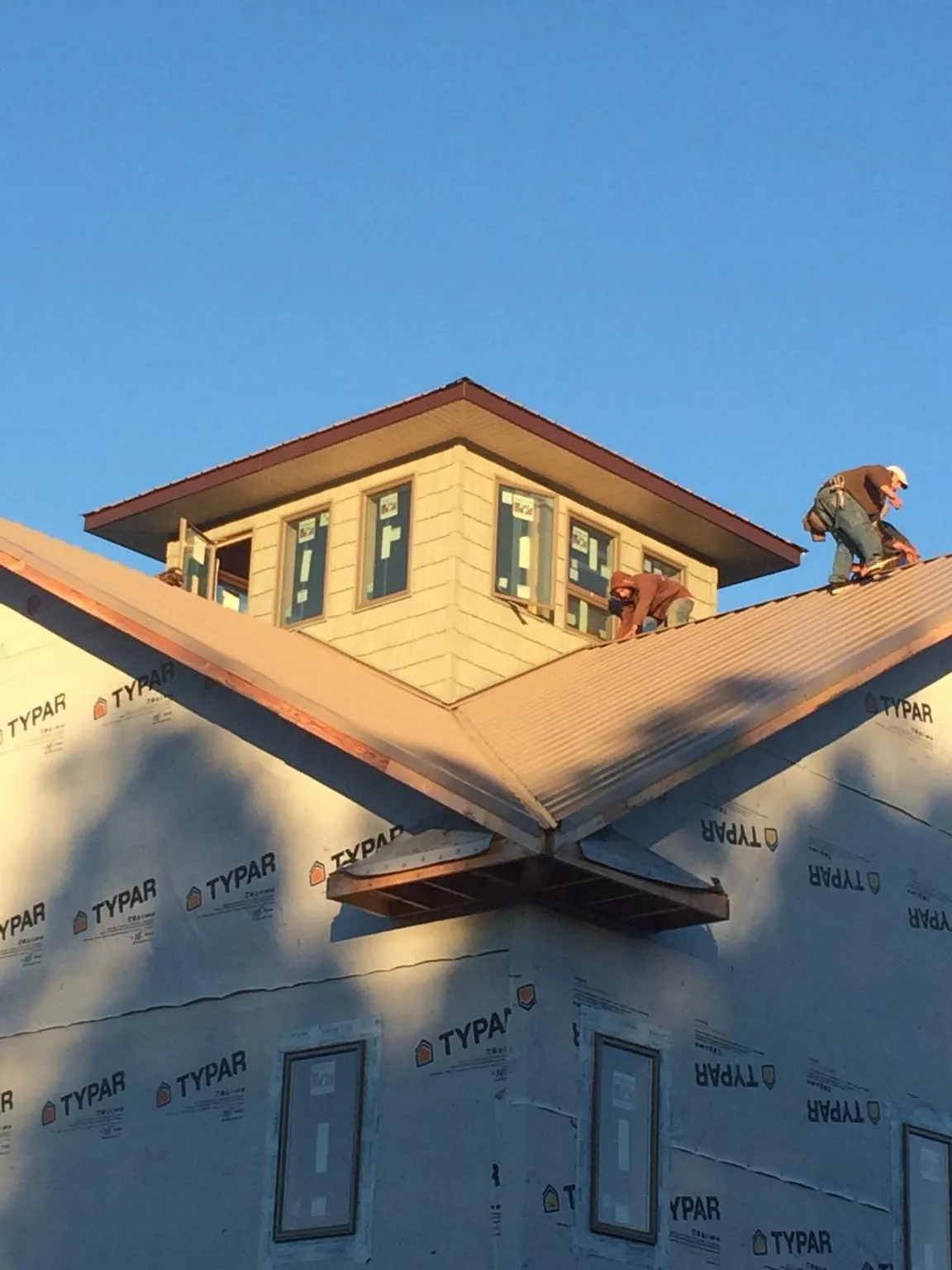 Roofers working around a rooftop cupola on a new metal roof at sunset — Roof Waterproofing in Center Moriches by Roofing Brothers